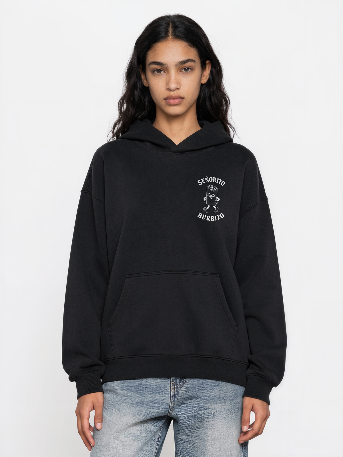 Female model wearing the Señorito Burrito black oversized hoodie, front view with small white burrito artwork on the left chest.