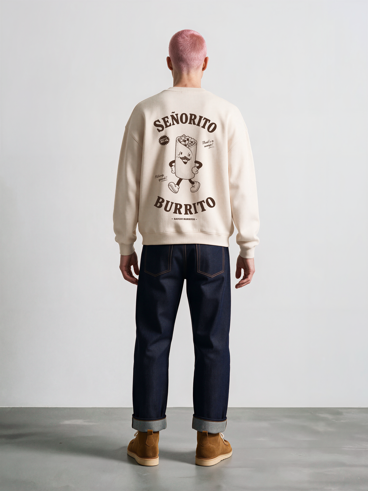 Male model wearing the Señorito Burrito ivory oversized sweatshirt, back view showing the dark brown large burrito character and lettering.