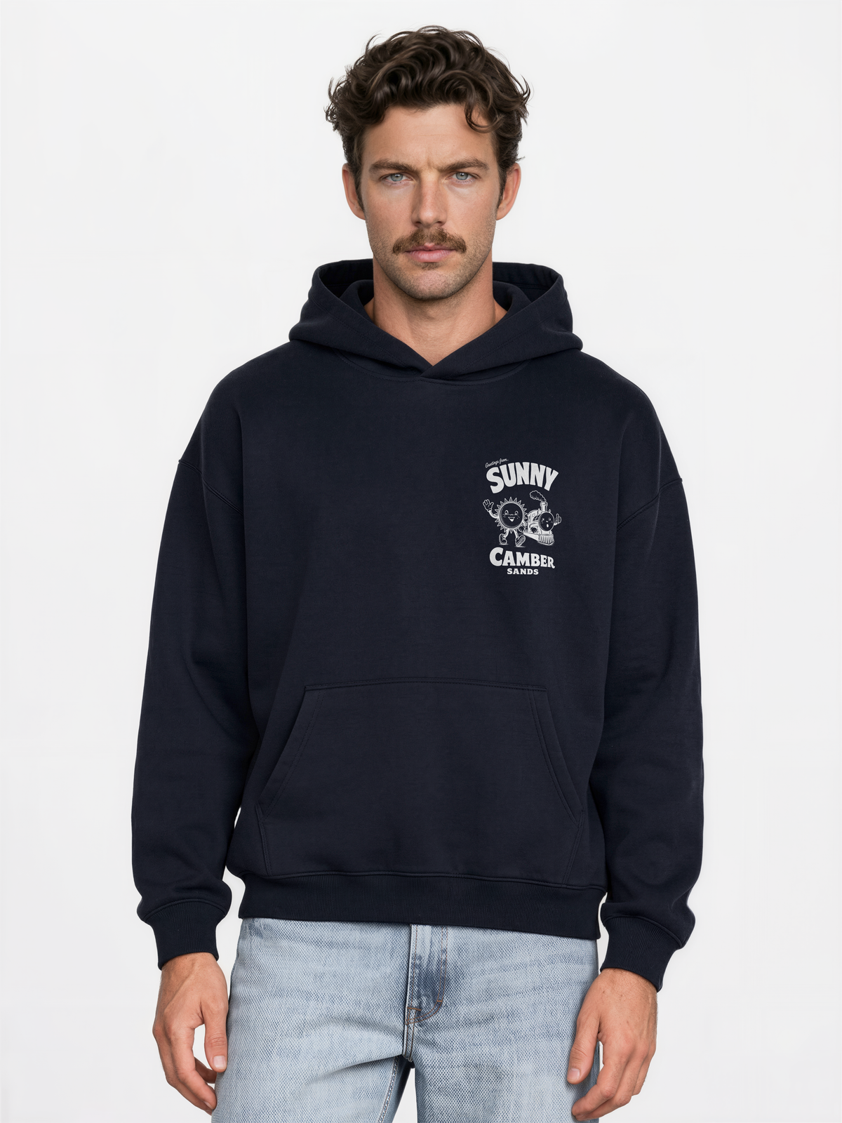 Sunny Camber Sands navy hoodie, front male model view, showing a small white sun and steam train chest print
