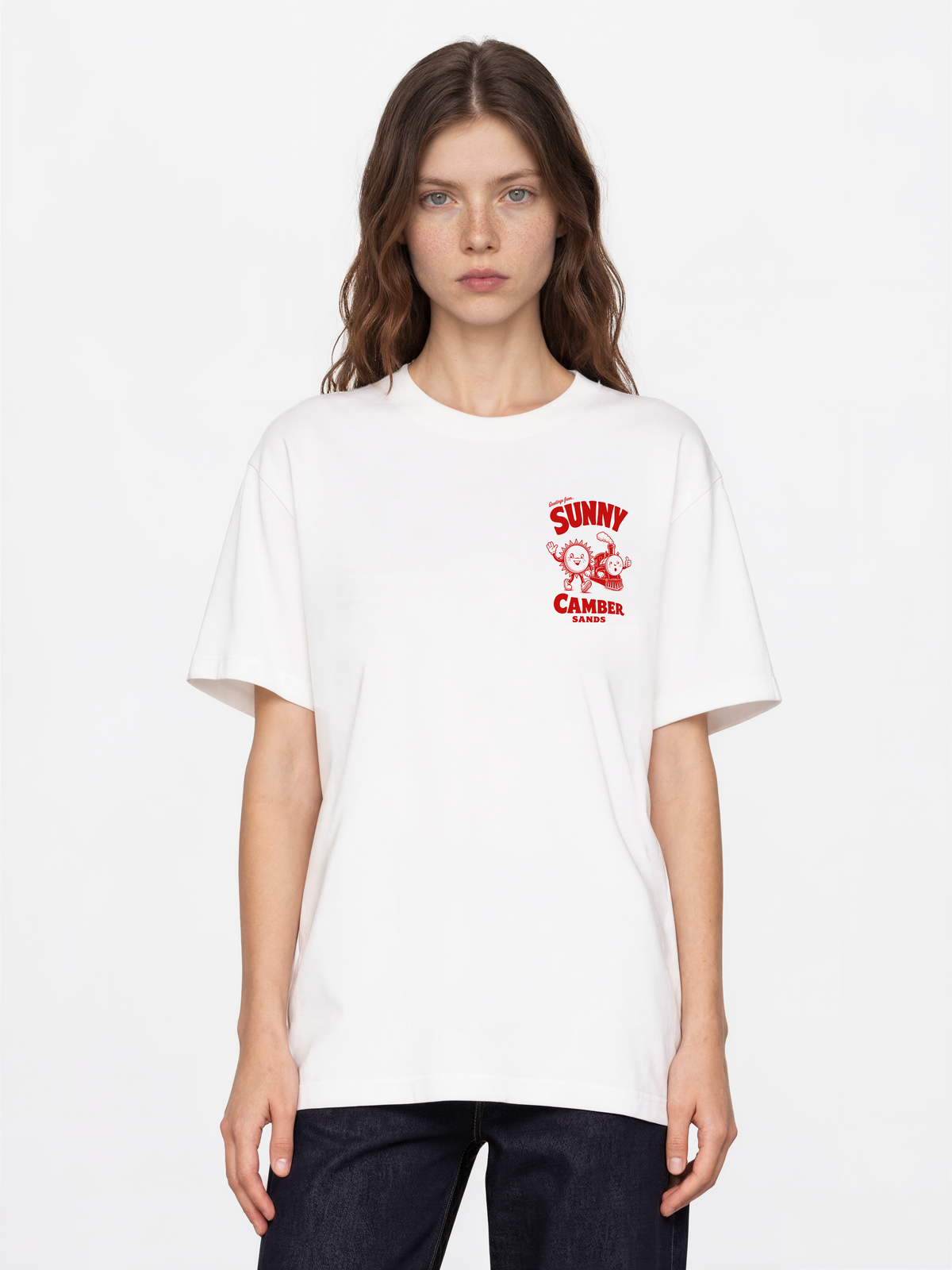 Sunny Camber Sands white T-shirt, front female model view, showing a small red sun and steam train chest print