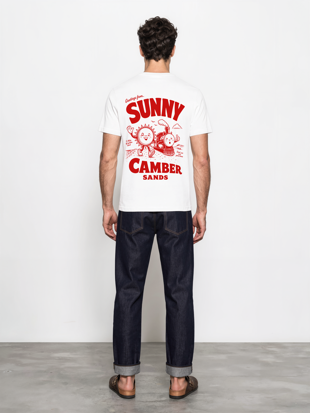 Sunny Camber Sands white T-shirt, back male model view, showing the larger red seaside sun and steam train back design