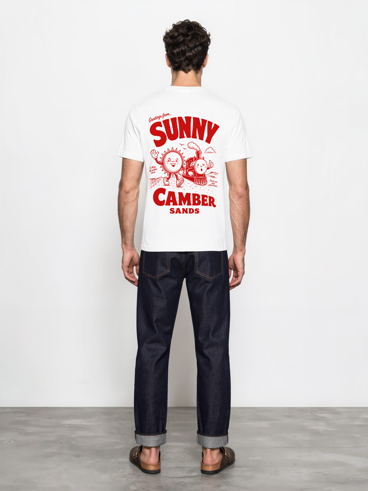 Sunny Camber Sands white T-shirt, back male model view, showing the larger red seaside sun and steam train back design