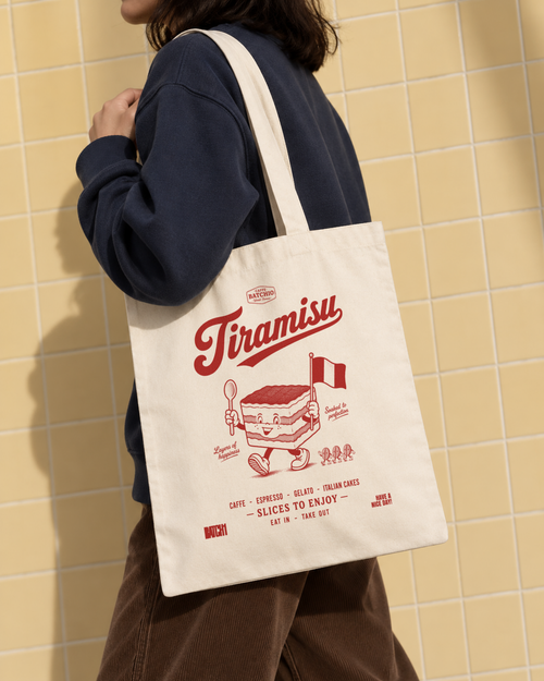Tiramisu natural cotton tote bag with red dessert print carried over the shoulder against butter-yellow tiles