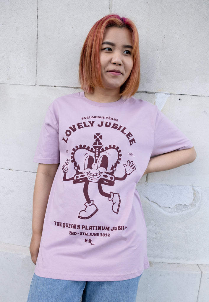 Model wears dusty purple unisex tshirt with 'Lovely Jubilee" slogan and crown character graphic