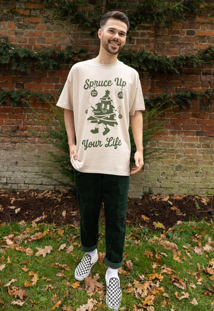 male model wears fun christmas t shirt in natural with spruce up your life slogan and tree character graphic