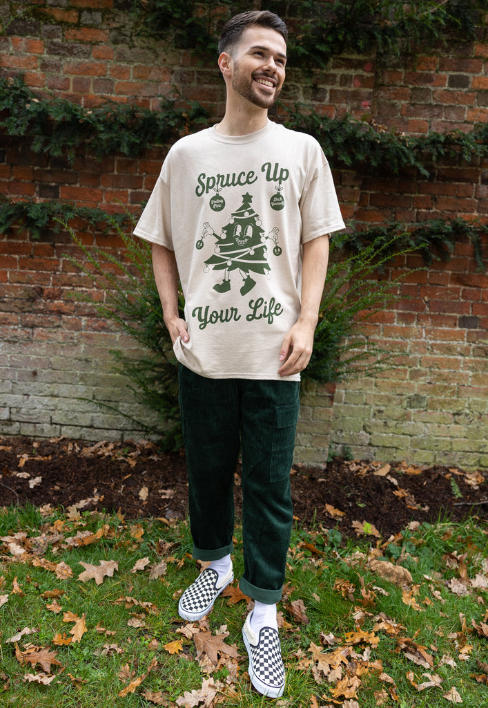male model wears christmas graphic t shirt with retro tree character graphic and spruce up your life slogan