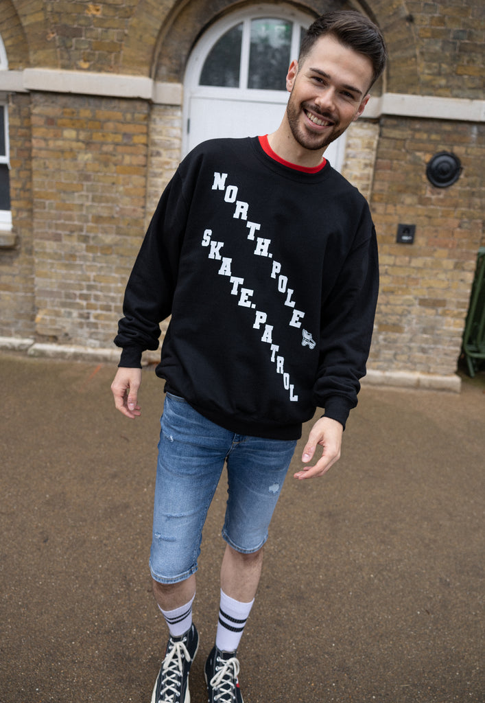 men's christmas jumper in black with white printed lettering reading north pole skate patrol