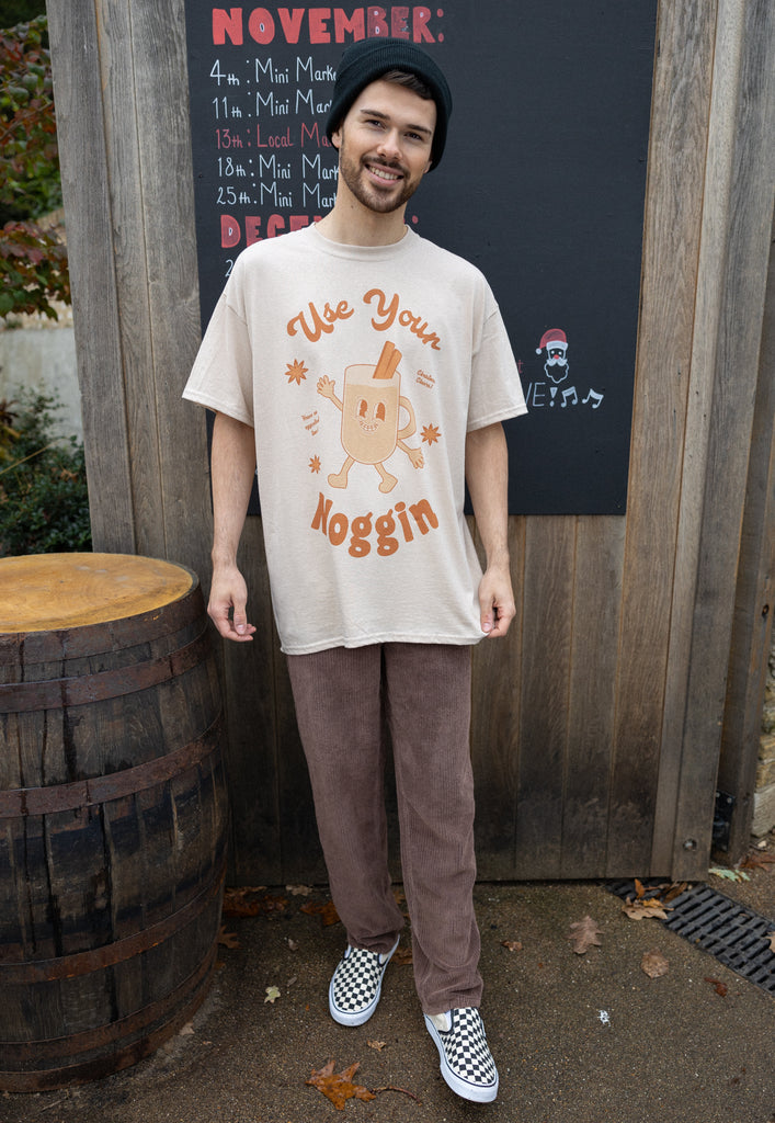 lifestyle image with male model wearing vintage style christmas t shirt with egg nog character graphic and 'use your noggin' slogan