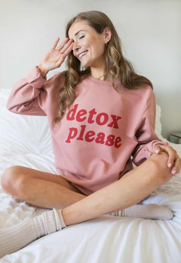 Model wears dusty pink loungewear sweater  with red printed Detox Please slogan