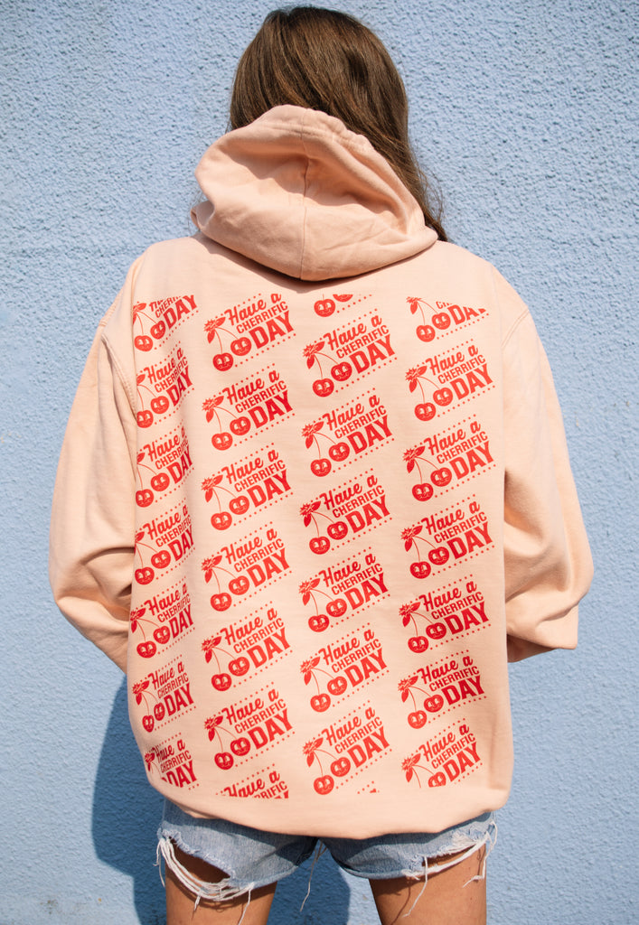 model wears back printed hoodie with repeat cherry logo