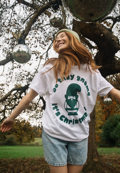 female model dances under disco ball wearing white printed t shirt with christmas gnome graphic and fun slogan 