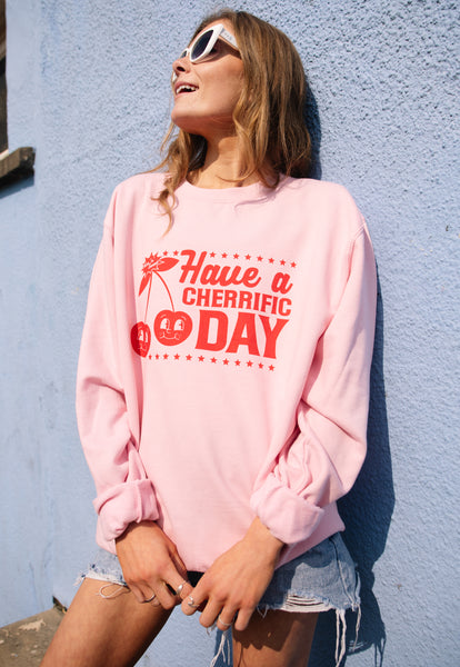 female model wears pink casual sweatshirt with printed cherry logo and have a cherrific day slogan
