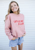 Model wears dusty pink sweatshirt with caffeine club slogan 