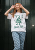 happy image of female model wearing white christmas themed t-shirt with vintage style graphics and positive slogan in unisex fit