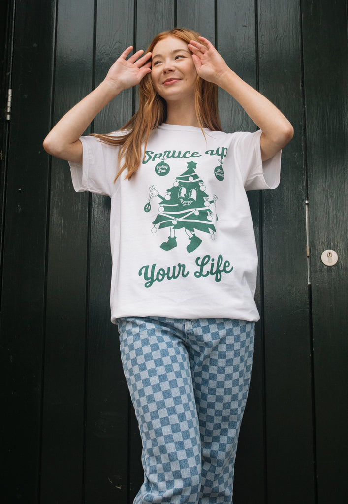 happy image of female model wearing white christmas themed t-shirt with vintage style graphics and positive slogan in unisex fit