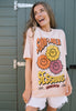 Model wears dusty peach t-shirt with festival slogan and flower character