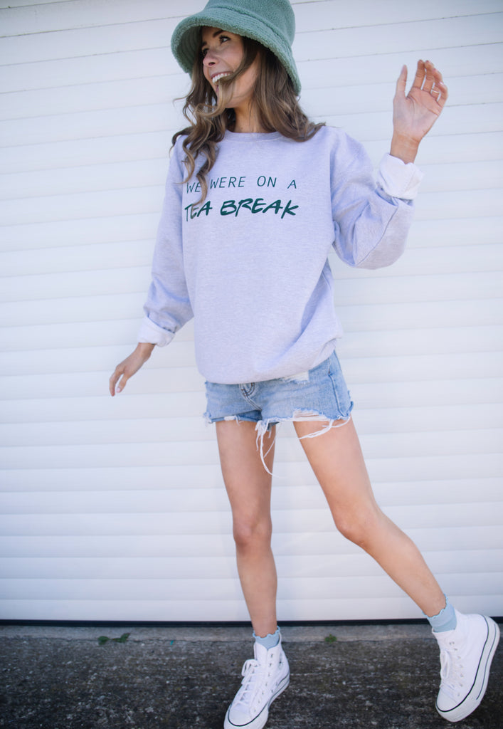 Model wears grey sweatshirt with We were on a Tea Break slogan 