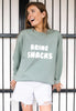 Model wears pastel green sweater with printed bring snacks slogan