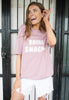 female model wears pastel purple t shirt with printed bring snacks slogan to front