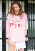 female model wears pink sweater printed with we need to taco slogan and taco graphic