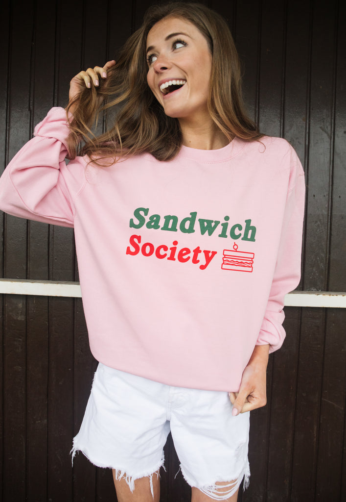 model wears pink sweater with printed sandwich slogan