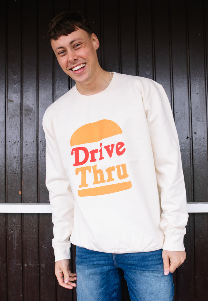 Model wears vanilla sweatshirt with Drive Thru slogan and burger graphic