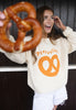 Model wears vanilla sweatshirt with Pretzellent slogan and pretzel graphic 