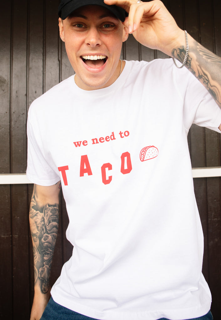 Model wears white tshirt with We Need To Taco slogan and taco graphic 
