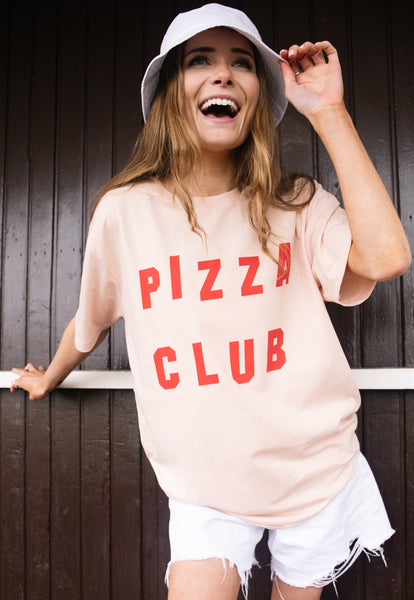Model wears dusty peach tshirt with Pizza Club slogan 