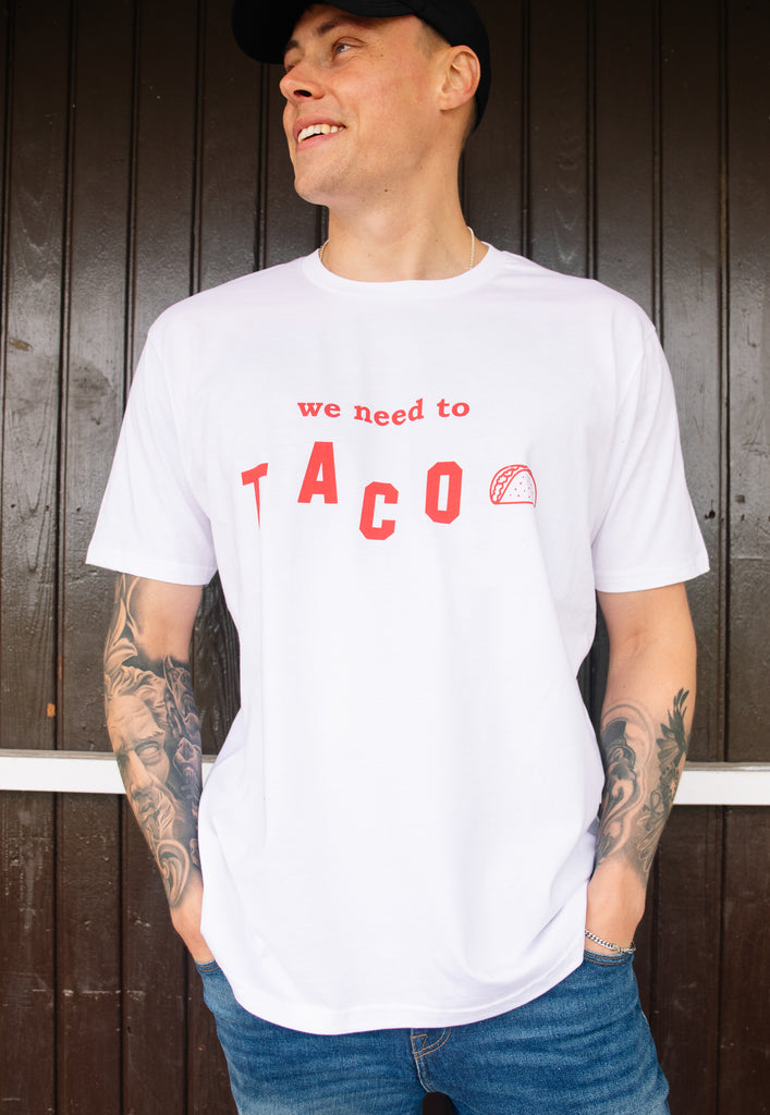 Model wears white tshirt with We Need To Taco slogan and taco graphic 
