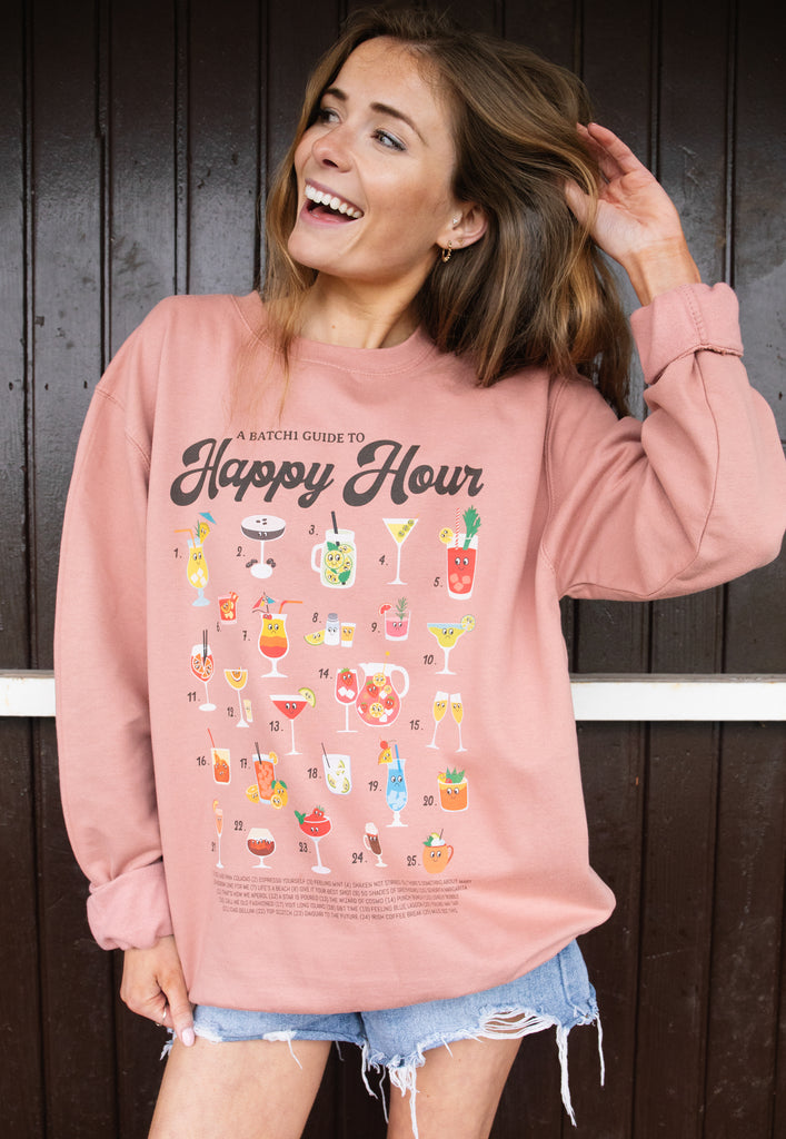 Model wears dusty pink sweatshirt with Happy hour slogan and cocktail guide print 