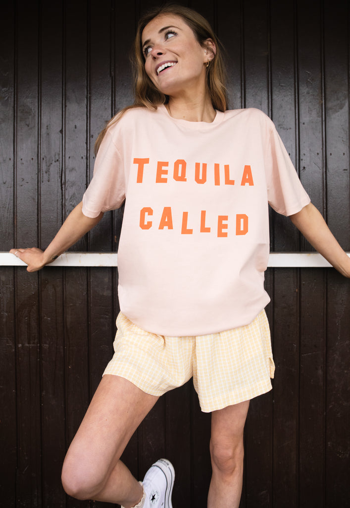 Model wears dusty peach tshirt with Tequila called slogan 