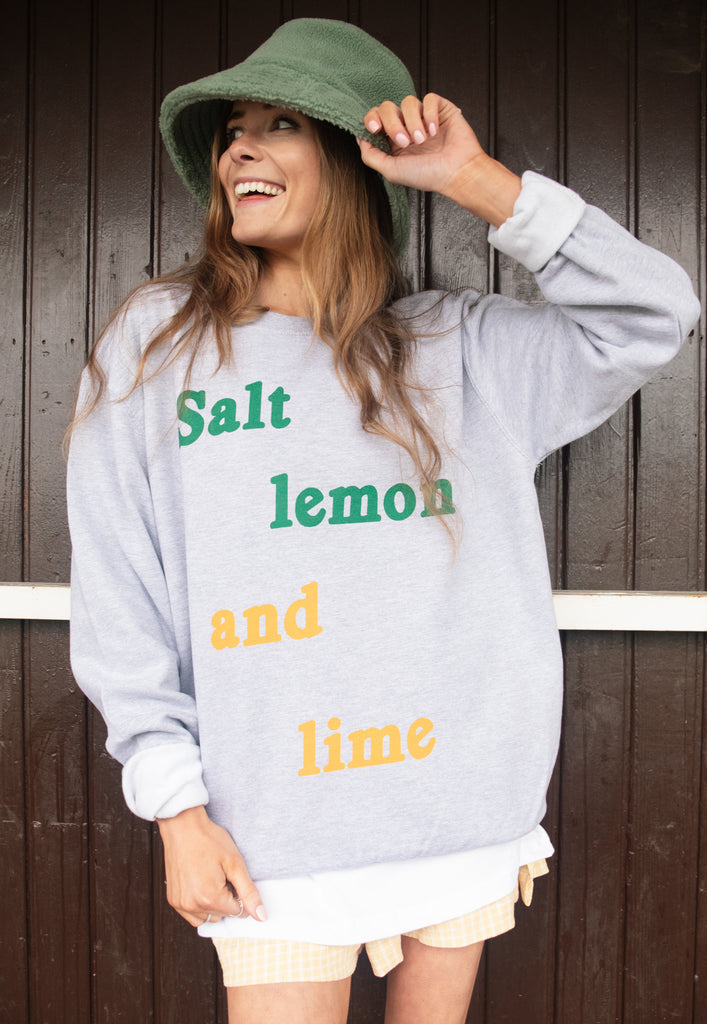 Model wears grey sweatshirt with Salt Lemon and Lime slogan 