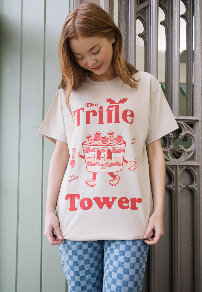 female model wears vintage style christmas t shirt in neutral sand colour with trifle character and trifle tower slogan