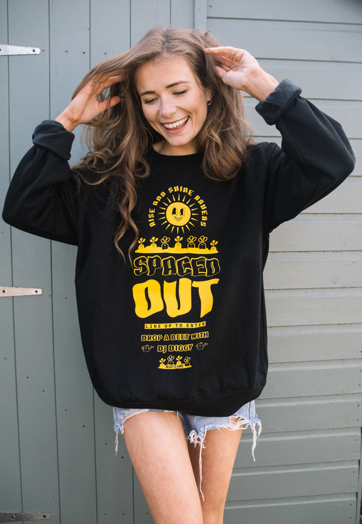 Model shown wearing black sweatshirt with bold yellow print and festival poster style design saying "Spaced Out"