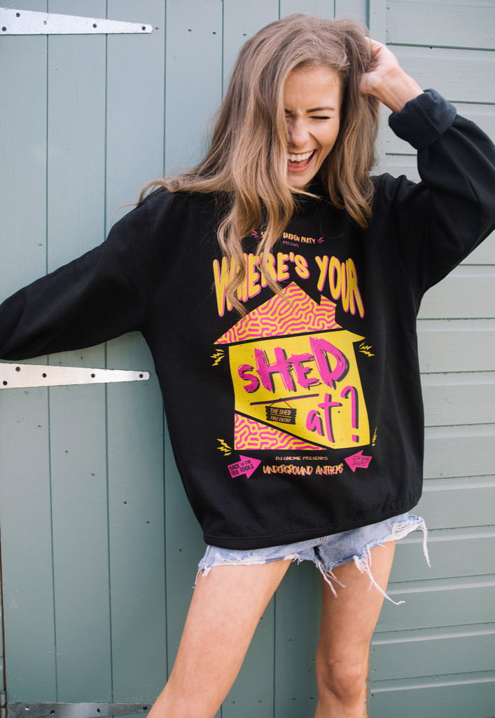 Model wears black sweatshirt printed with 90s style festival graphics, shed logo and "Where's Your Shed At" slogan