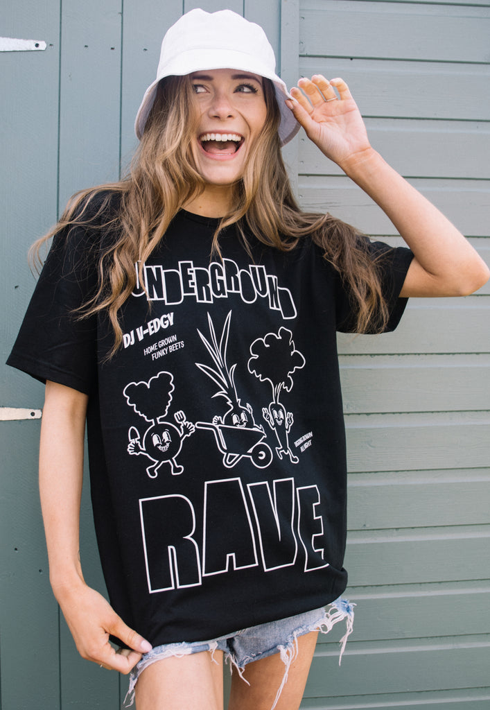 Model wears Black festival t-shirt with 'underground rave' slogan and veggie characters in white print