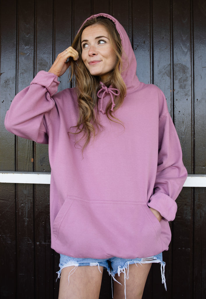 model is wearing relaxed fit purple hooded sweatshirt no print is on front of sweater only the back