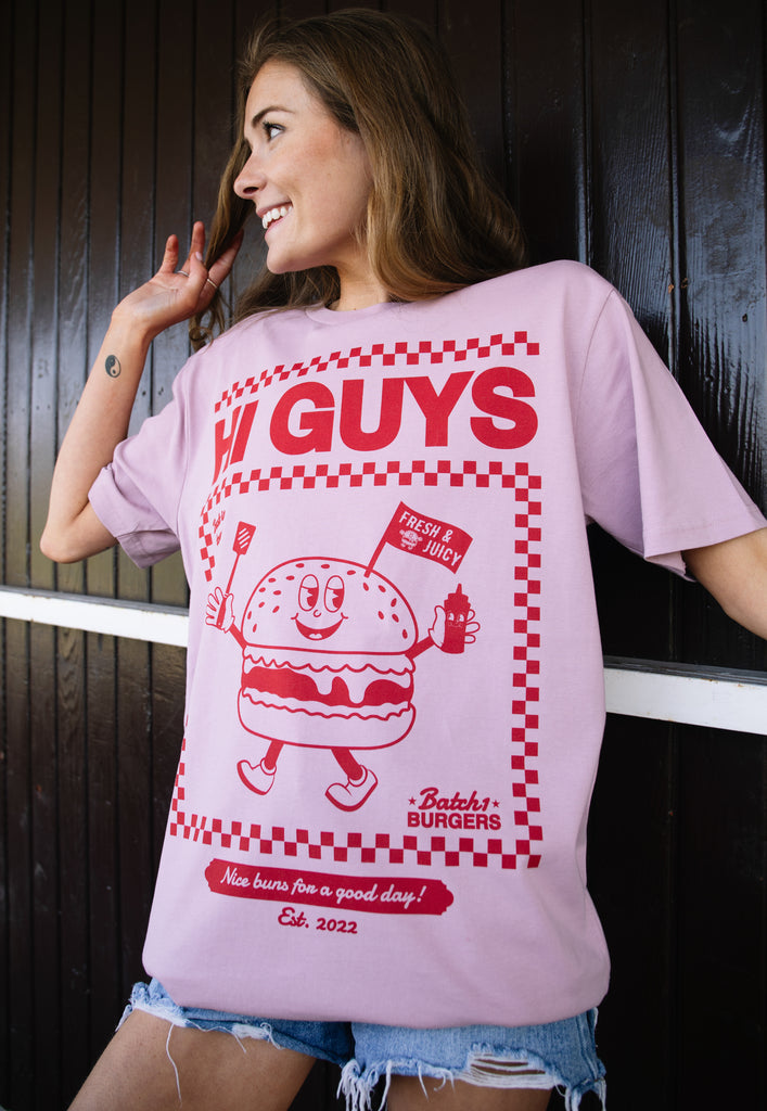 Model wears dusty purple tshirt with Hi Guys Slogan and burger character graphic 