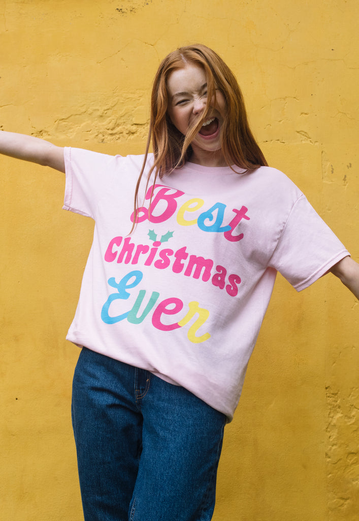 joyful image of female model wearing relaxed christmas t shirt with bold 'best christmas ever' slogan print in bright colours 