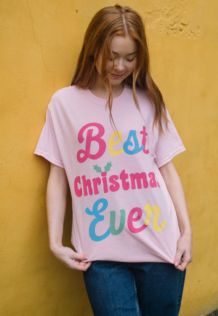 close up of female model wearing pink christmas t shirt with bright print that reads 'best christmas ever'