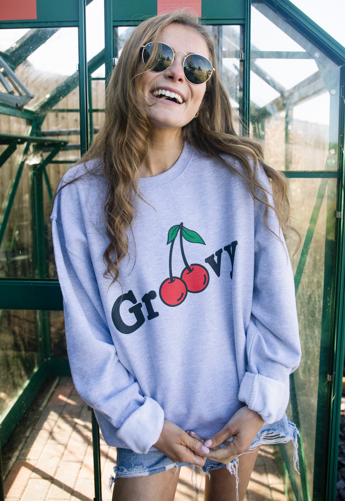 Model wears grey sweatshirt with groovy slogan and cherry graphic 