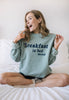 pastel green sweatshirt with printed Breakfast in Bed slogan on front shown on female model 