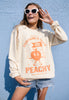 Model wears vanilla sweatshirt with peach character graphic
