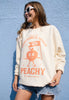 Model wears vanilla sweatshirt with vintage peach graphic and positive slogan
