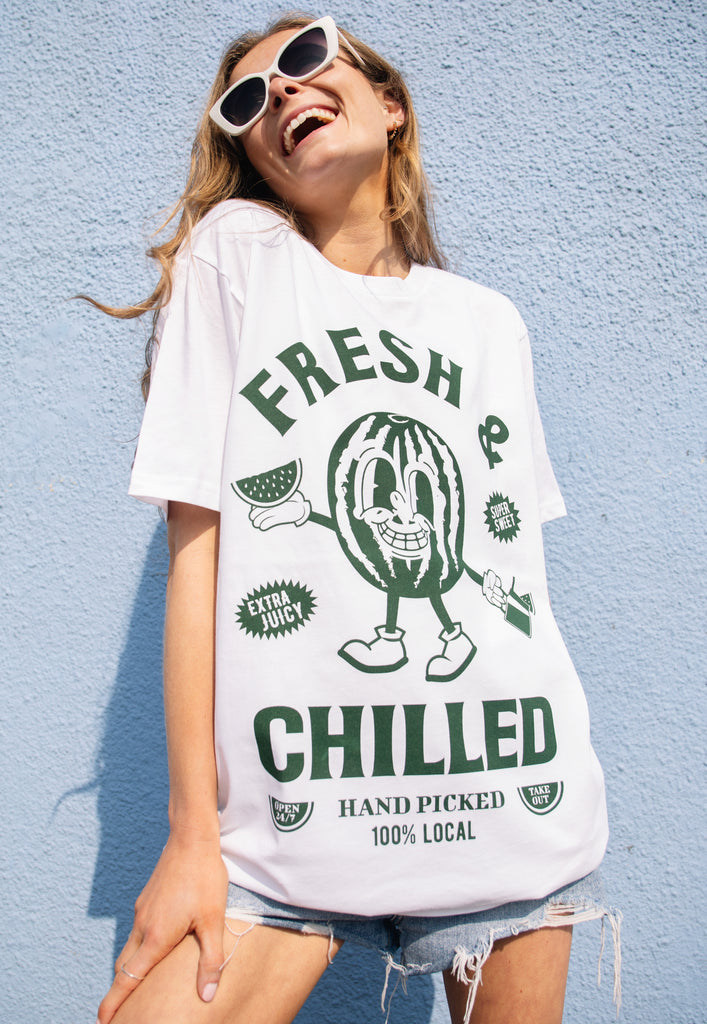 Model wears white t-shirt with fruit character and slogan in green