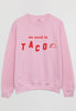 flatlay of casual pink sweatshirt printed with we need to taco slogan