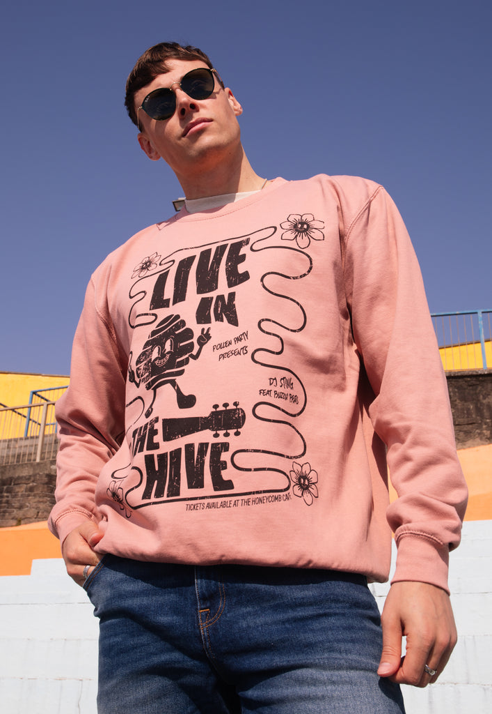 Model wears dusty pink sweatshirt with Live in The Hive festival slogan 