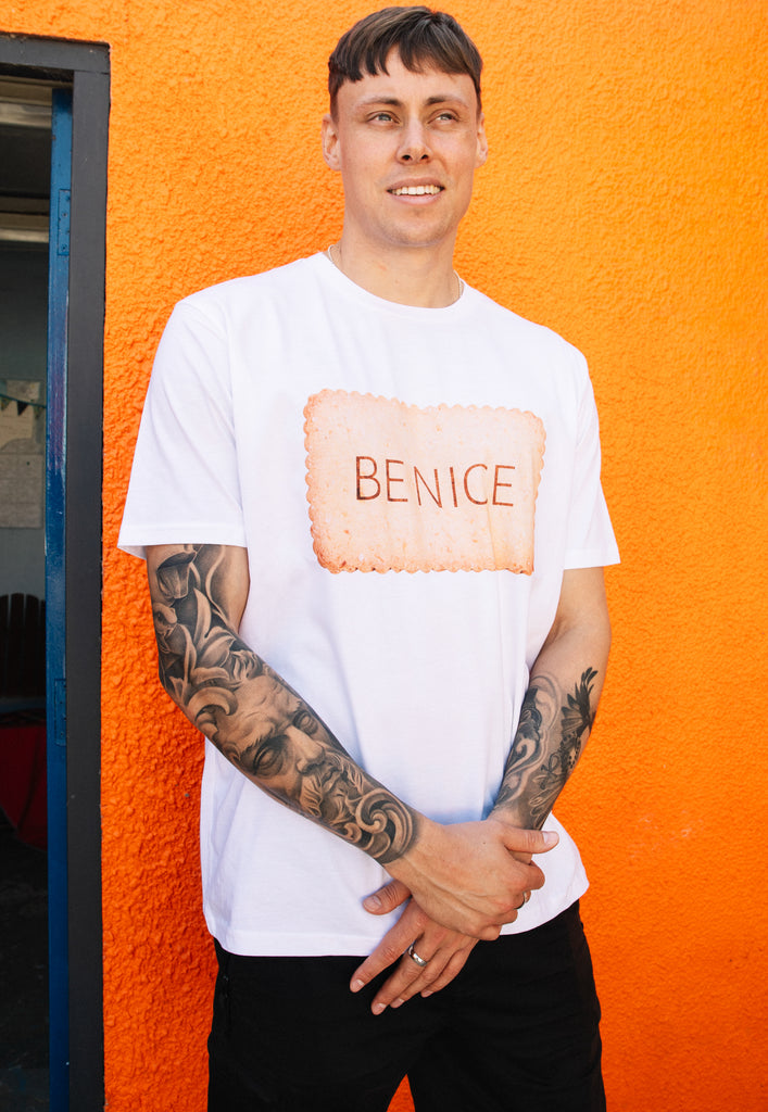 Model wears white tshirt with Be Nice slogan and biscuit graphic 